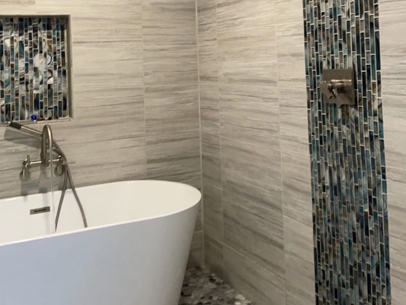 Finished bathroom with a freestanding tub and a mosaic tile accent