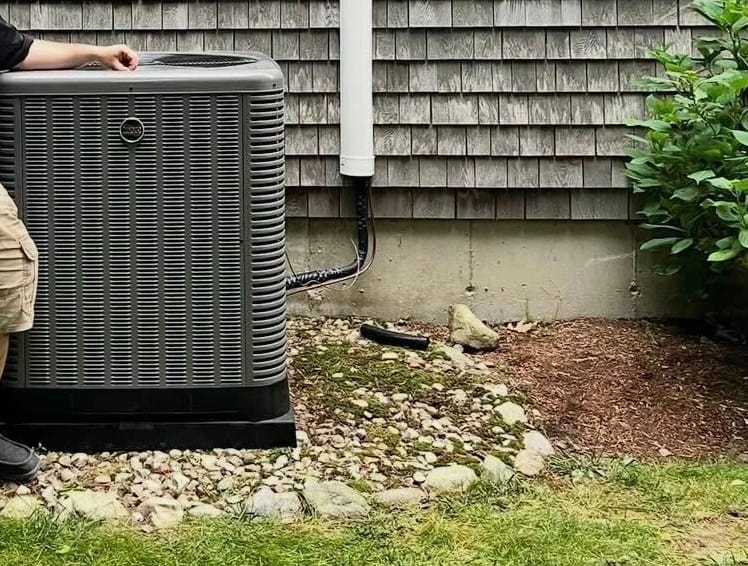 A newly set outdoor condenser on its pad in a stone bed