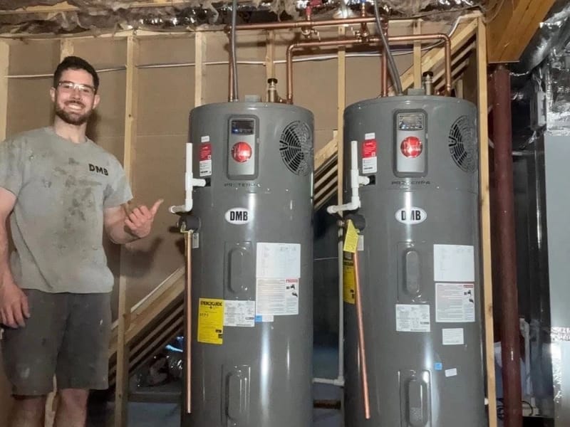 DMB tech beside two new water heaters wearing DMB stickers