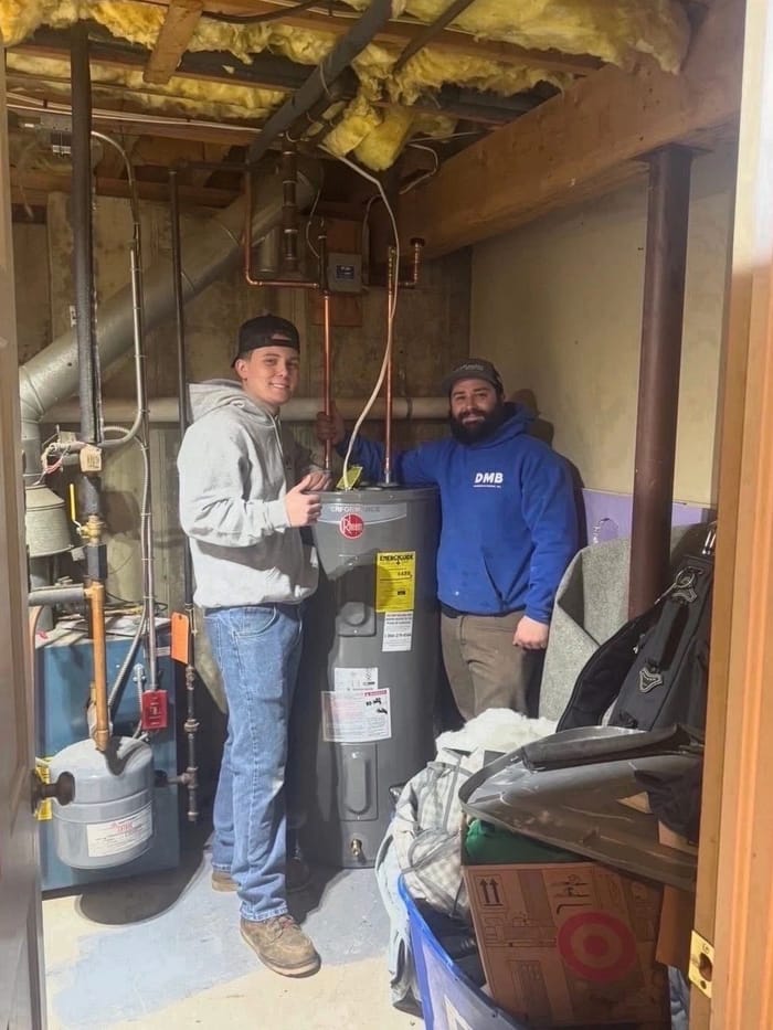 Dean and a young tech beside a new water heater in a mechanical room